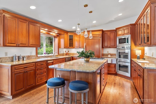 kitchen featuring light wood finished floors, appliances with stainless steel finishes, a kitchen island, and brown cabinets