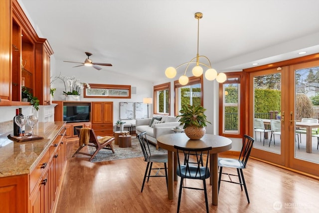 dining space with ceiling fan, light wood-style flooring, and vaulted ceiling