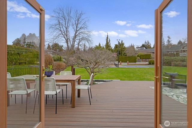 wooden terrace featuring outdoor dining area and a lawn