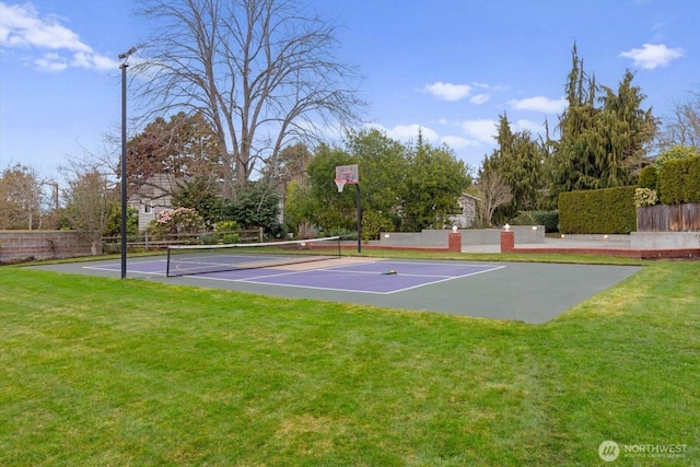 view of sport court featuring a tennis court, a lawn, and fence