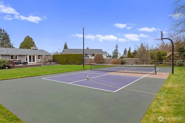 view of tennis court with fence and a lawn