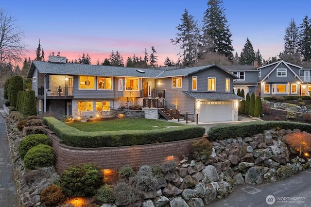 view of front of house with a garage, concrete driveway, a balcony, stone siding, and a chimney