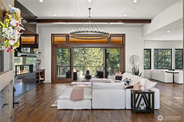 living room with beamed ceiling, dark hardwood / wood-style floors, and a chandelier