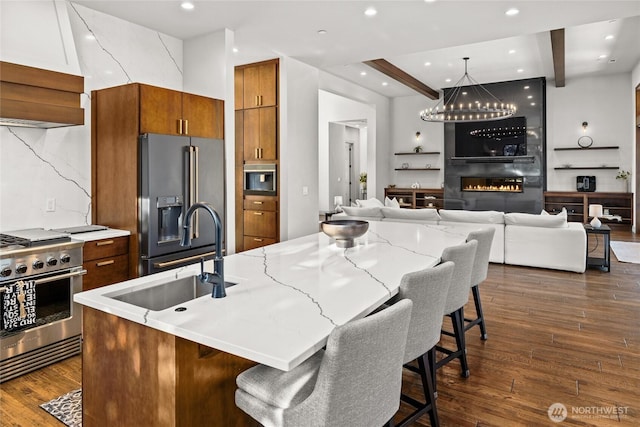 kitchen featuring a kitchen island with sink, high end fridge, stainless steel stove, and a kitchen bar