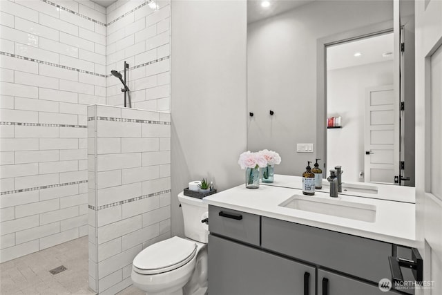 bathroom featuring vanity, toilet, and a tile shower