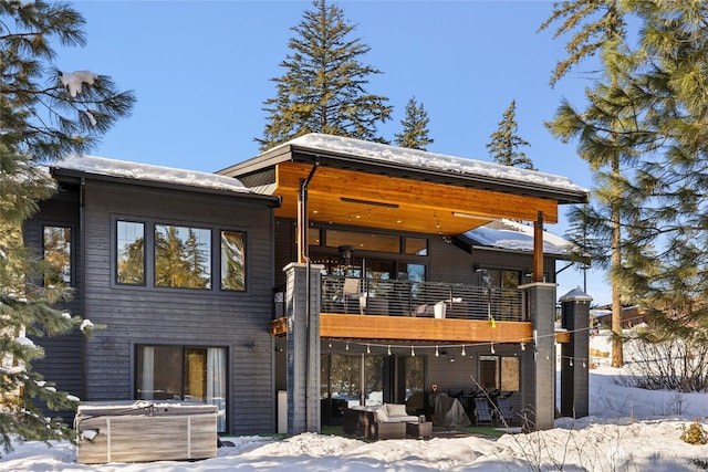 snow covered property featuring a hot tub and a balcony