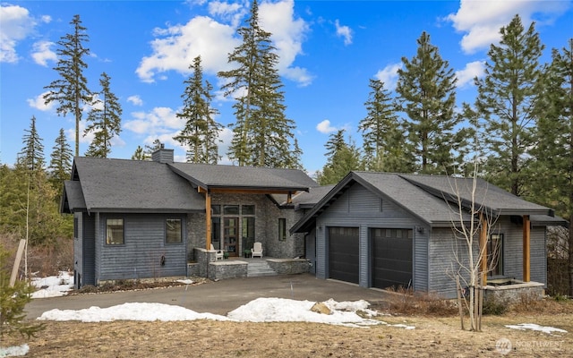 view of front of house with roof mounted solar panels, an attached garage, a chimney, and driveway