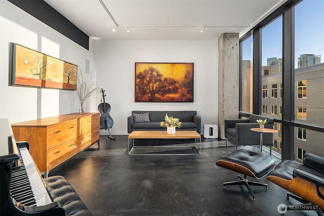 living area with a view of city, rail lighting, and finished concrete flooring