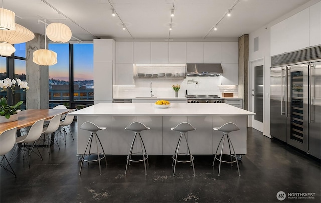 kitchen featuring decorative backsplash, under cabinet range hood, built in refrigerator, range, and modern cabinets