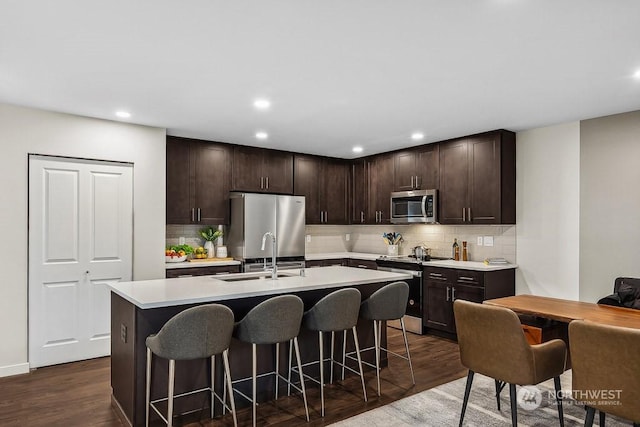 kitchen featuring stainless steel appliances, sink, dark brown cabinetry, and a kitchen breakfast bar