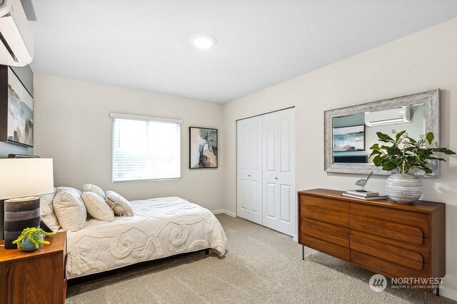 bedroom with a closet, light colored carpet, and a wall unit AC