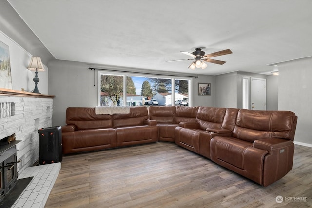 living room featuring a brick fireplace, light hardwood / wood-style floors, and ceiling fan