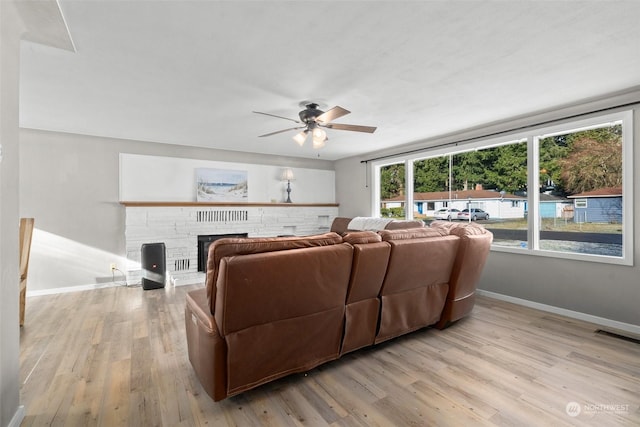 living room with ceiling fan, a fireplace, and light hardwood / wood-style floors