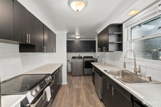 kitchen with sink, washer and clothes dryer, stainless steel appliances, tasteful backsplash, and light wood-type flooring