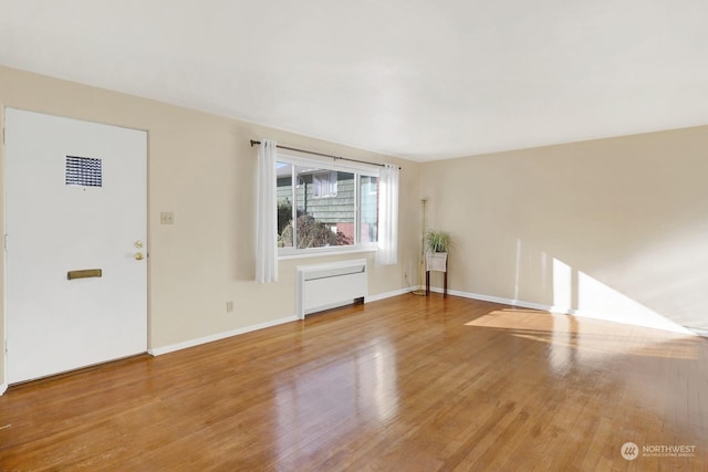 unfurnished living room featuring hardwood / wood-style flooring and radiator heating unit