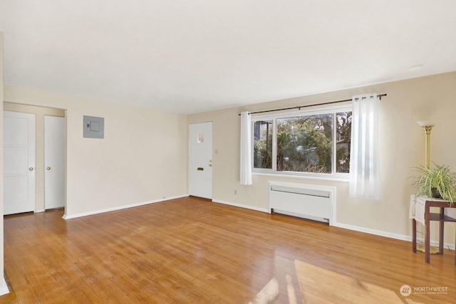 unfurnished living room with radiator, electric panel, and hardwood / wood-style floors