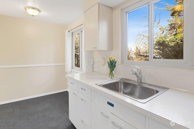 kitchen with white cabinets, sink, and dark colored carpet