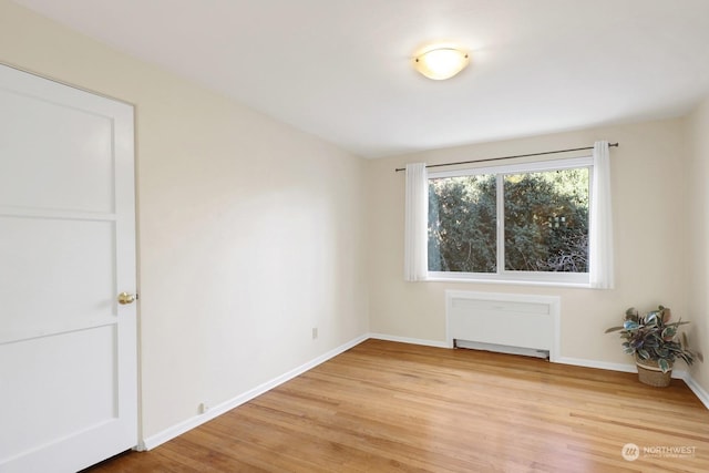 unfurnished room featuring radiator heating unit and light wood-type flooring