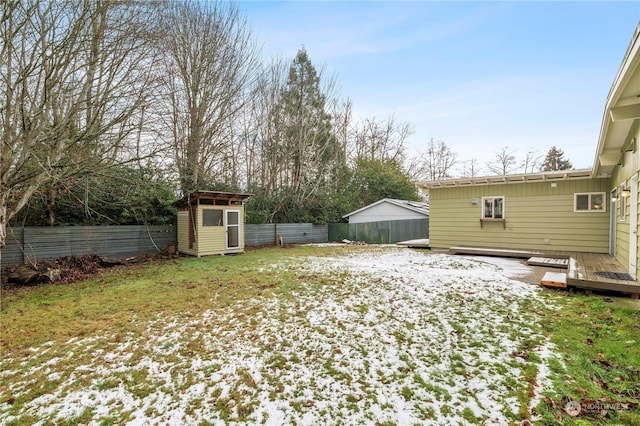 snowy yard featuring a deck and a storage shed