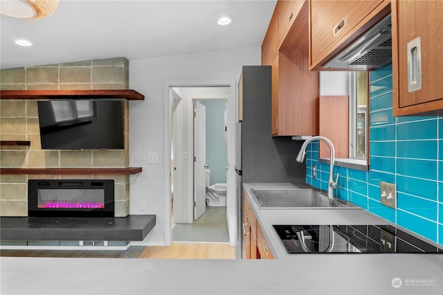 kitchen featuring tasteful backsplash, black electric stovetop, sink, and custom range hood