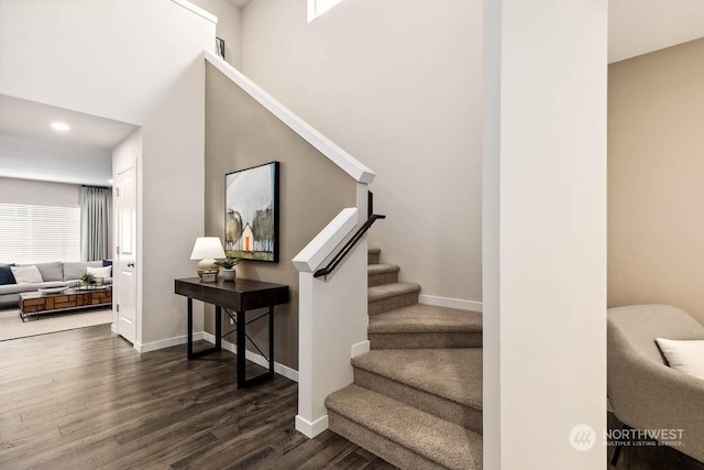 stairs with hardwood / wood-style floors and a high ceiling