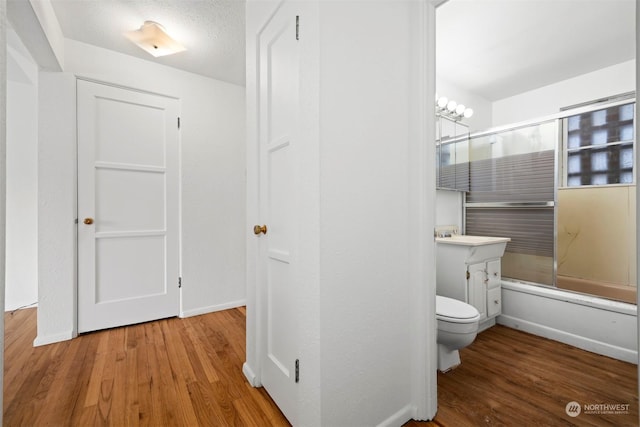 full bathroom with vanity, toilet, combined bath / shower with glass door, and hardwood / wood-style floors