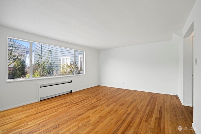 spare room featuring radiator heating unit and light hardwood / wood-style flooring