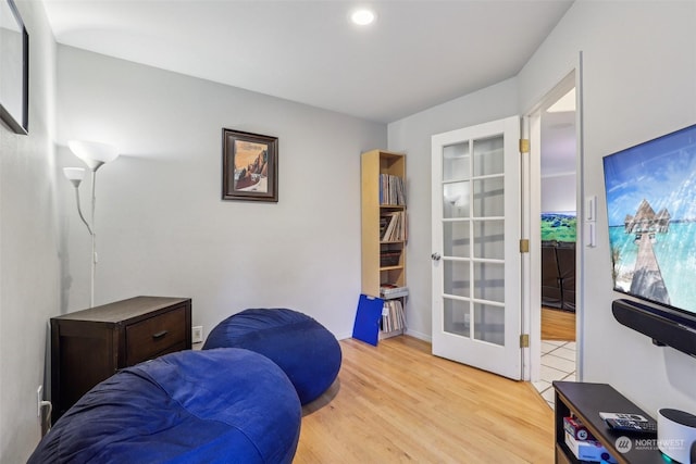 living area with french doors and light hardwood / wood-style floors