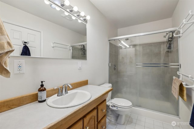 bathroom featuring vanity, toilet, a shower with shower door, and tile patterned flooring