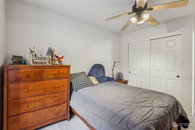 bedroom featuring light colored carpet, ceiling fan, and a closet