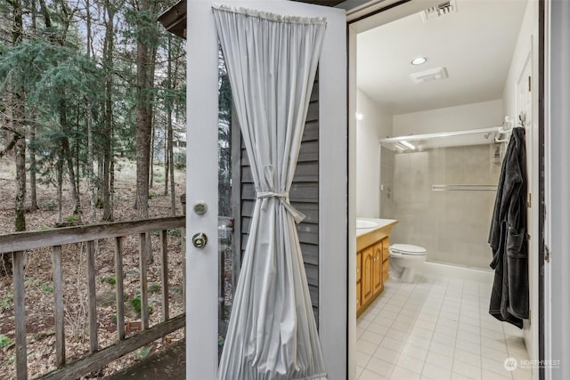 bathroom with a shower, vanity, tile patterned floors, and toilet