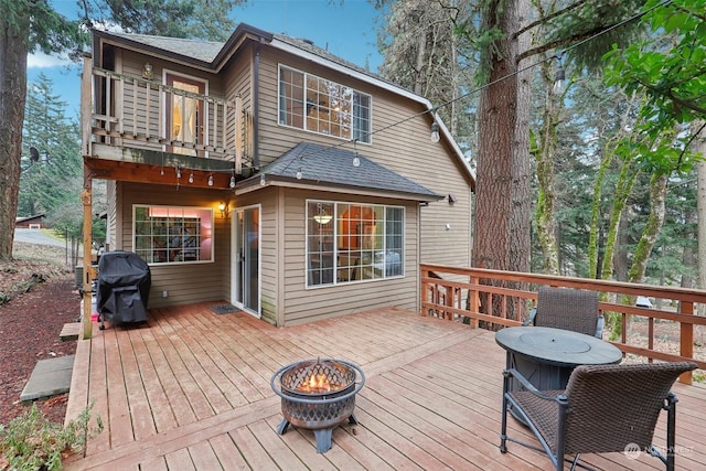 wooden deck with grilling area and an outdoor fire pit