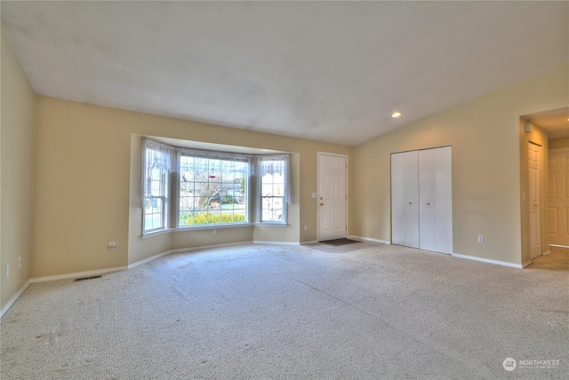 empty room featuring light colored carpet and vaulted ceiling