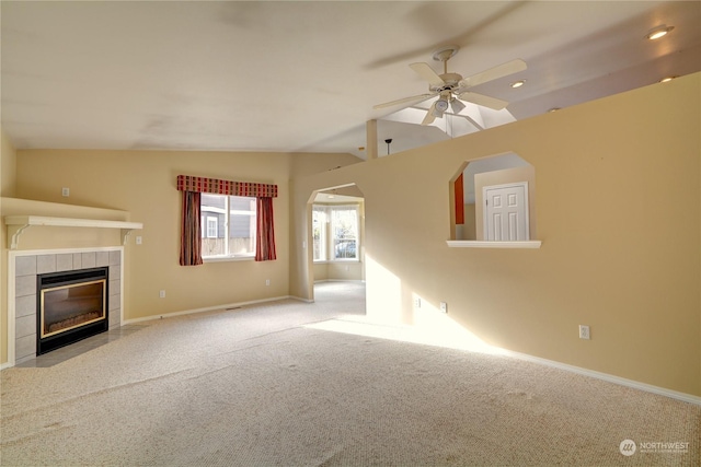 unfurnished living room with light colored carpet, vaulted ceiling, a tile fireplace, and ceiling fan