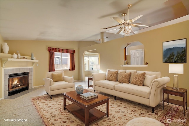 living room featuring a tiled fireplace, lofted ceiling, and ceiling fan