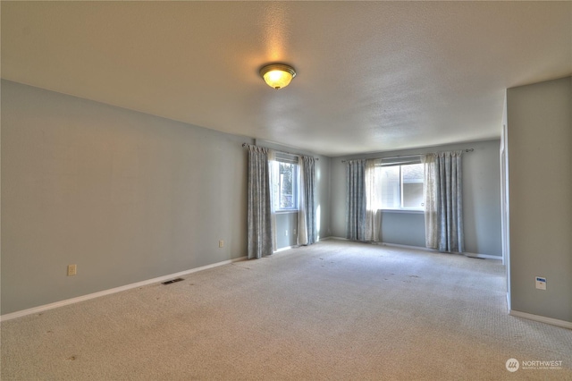 empty room with light carpet and a textured ceiling