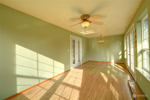 unfurnished sunroom featuring ceiling fan with notable chandelier and french doors