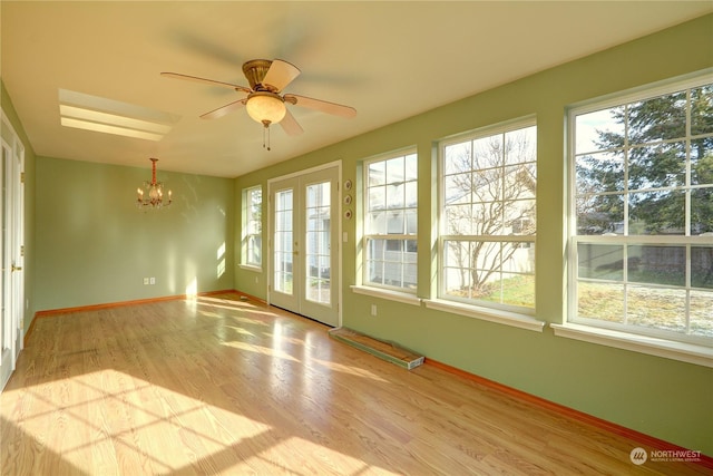 unfurnished sunroom featuring ceiling fan with notable chandelier and french doors