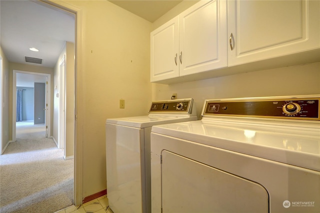 laundry room with separate washer and dryer, light carpet, and cabinets