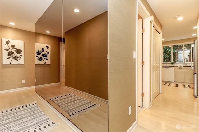 hallway with sink and light hardwood / wood-style flooring