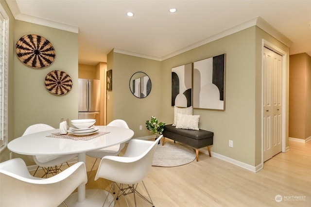 dining space featuring ornamental molding and light hardwood / wood-style flooring