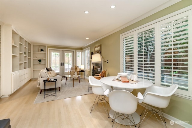 dining room with crown molding, french doors, and light wood-type flooring