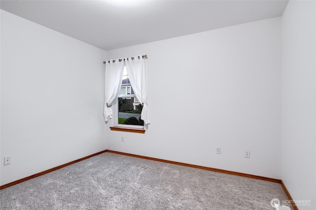 carpeted spare room featuring baseboards