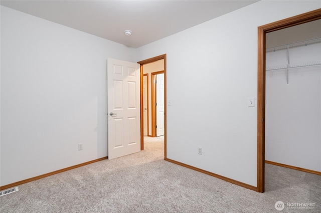 unfurnished bedroom featuring a closet, carpet flooring, visible vents, and baseboards