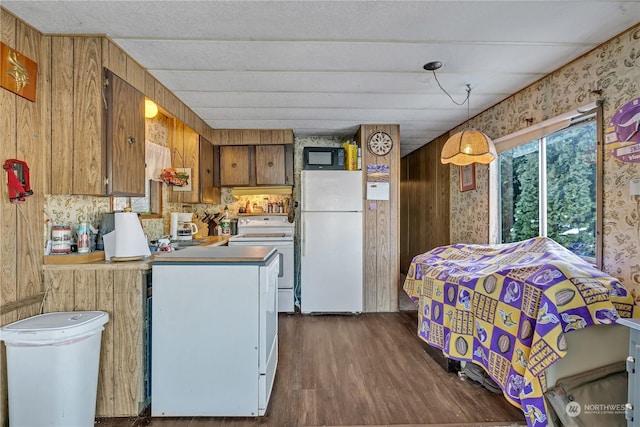 kitchen with dark hardwood / wood-style floors, kitchen peninsula, white appliances, and decorative light fixtures