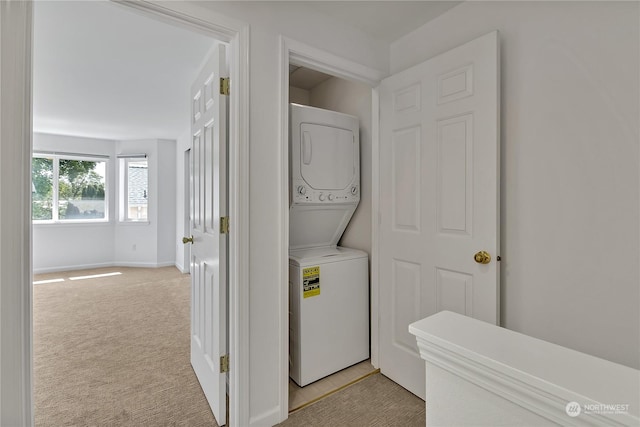 laundry room featuring stacked washer / dryer, laundry area, light carpet, and baseboards