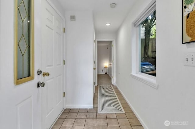 hall featuring baseboards and light tile patterned flooring