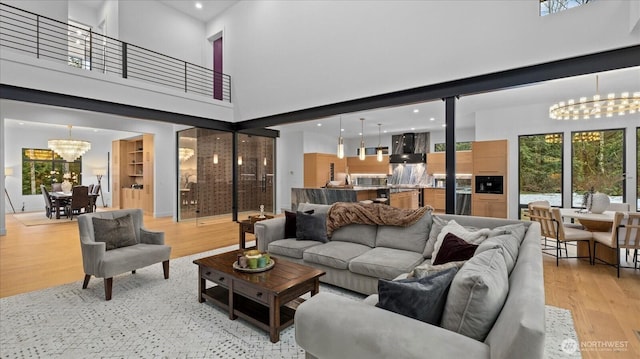 living room featuring light wood-type flooring, an inviting chandelier, and a towering ceiling