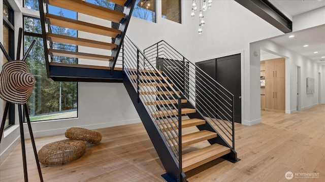 stairs with a chandelier, a high ceiling, and hardwood / wood-style floors