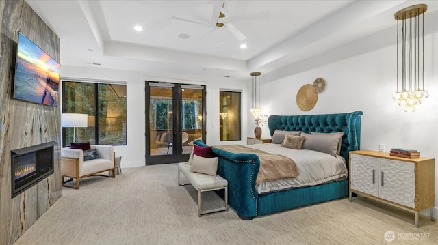 carpeted bedroom with a fireplace, access to exterior, french doors, and a raised ceiling